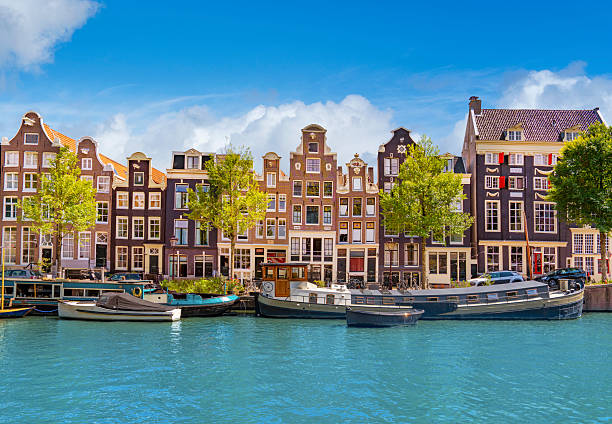 Traditional gabled houses along Singel canal in Amsterdam on a sunny summer day